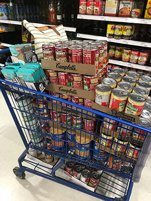 Shopping cart stacked with canned goods for donation to Simply Give partner Love INC