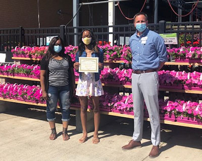 Fred and Lena Meijer scholarship recipient Moaray Hunter-Moore with award at garden center in Knapp's Corner, Michigan store