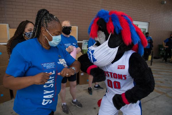 Meijer team member bumping elbows with Detroit Pistons mascot, Hooper, at shoe donation event