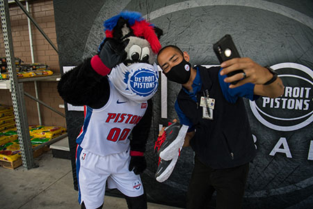 Meijer team member taking selfie with Detroit Pistons mascot, Hooper, at shoe donation event