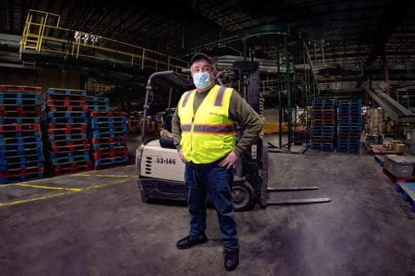 Meijer team member of 50 years, in distribution center with equipment and crates