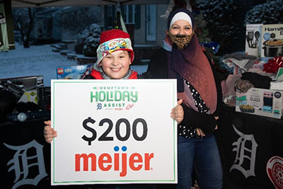 Young boy holding $200 Meijer gift card from Holiday Assist initiative partners Detroit Red Wings, Detroit Tigers and Meijer