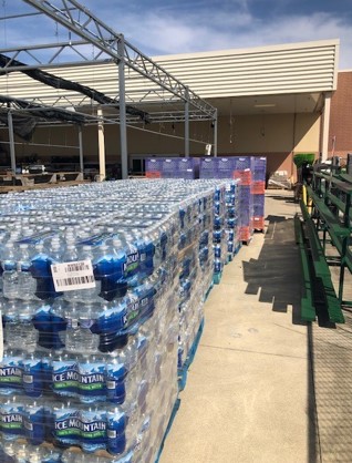 Dozens of cases of water bottles sit on pallets behind a Meijer store