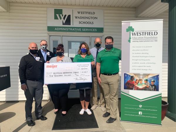 Meijer team members and Westfield Washington School administrators stand holding a giant check for $10,000 to Westfield Washington Schools in front of the school administration offices next to a sign for the Westfield Education Foundation.