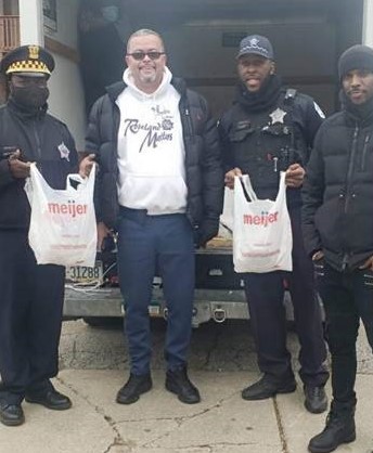 Chicago police officers and Roseland Matters volunteer holding Meijer bags full of food