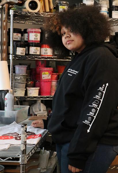 WMCAT student artist Minni Peters wearing the Black History Month sweatshirt she helped design for Meijer in the Ambrose studio