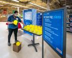 Greeter Briaja Lyons arranges yellow plastic hard hats on a table at the entrance of the Portage, Mich. Meijer.