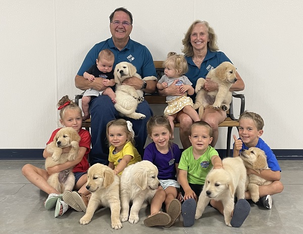 Kevin Hurn and his wife with their seven grandchildren, each holding a puppy