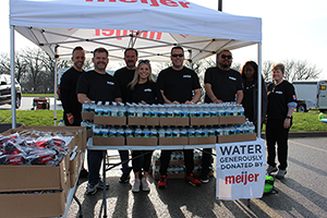 Meijer team members stand together behind water bottles under a tent.