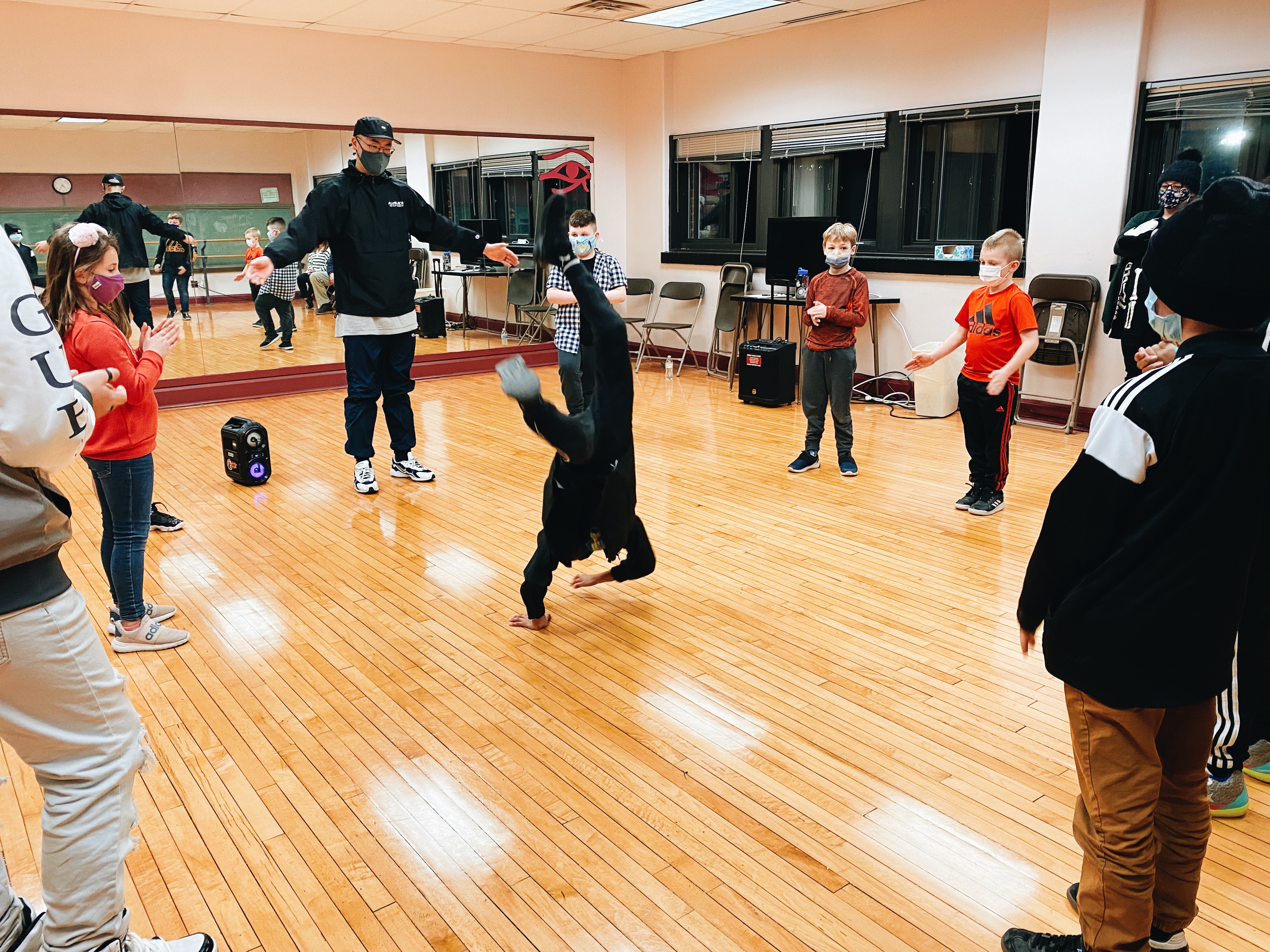Students at All of the Above Hip Hop Academy cheer on a peer doing a trick on balanced on their hands in the middle of the dance circle
