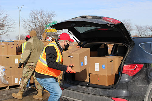 A volunteer loads boxes of frozen turkeys into the trunk of a car.