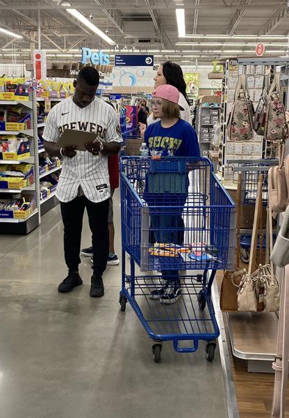 Milwaukee Brewers player Jonathan Davis examines a student’s school shopping list in the Meijer aisle