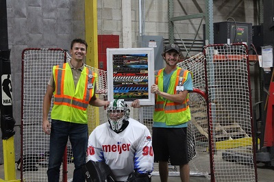 Meijer team members hold the plaque for the Walker, Mich. distribution center’s annual hockey shootout event in front of a hockey goal
