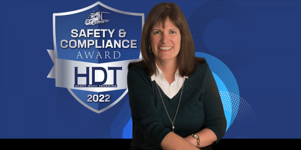 Carol Heinowski in front of Heavy Duty Trucking 2022 Safety & Compliance Award Logo