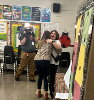 Store Director Sheila Dowgiert surprises Teacher Donna Kucera with a gift card in her classroom
