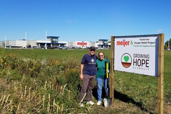 Burt and Lida Keefer pose by Meijer Thumb Area Hunger Relief Project Sign